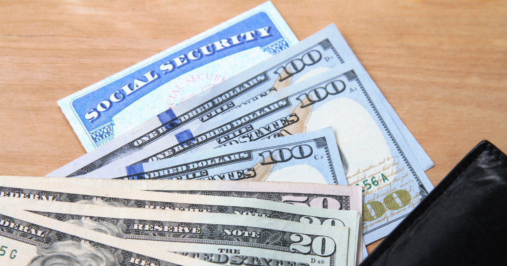 Social security card and dollar bills spread on desktop.