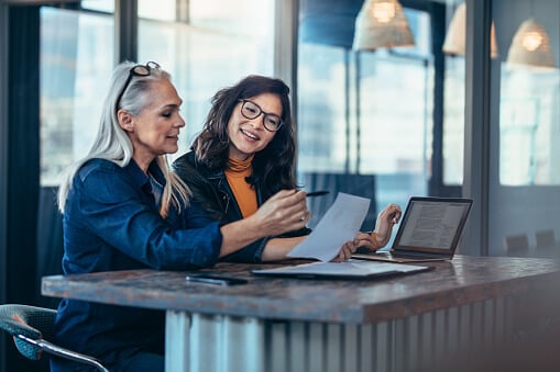 two women analyzing 403b vs 401k documents in an office